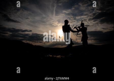 Martial arts sword fighting silhouettes at sunset Stock Photo