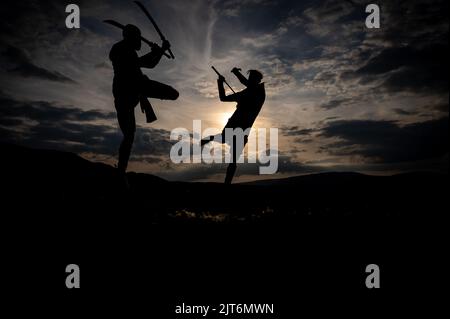 Martial arts sword fighting silhouettes at sunset Stock Photo