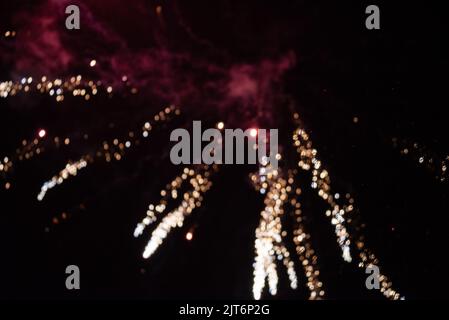 Blurred background. Fireworks in the night sky in the distance. Blurry sparkling fireworks on New Year's Eve. Stock Photo