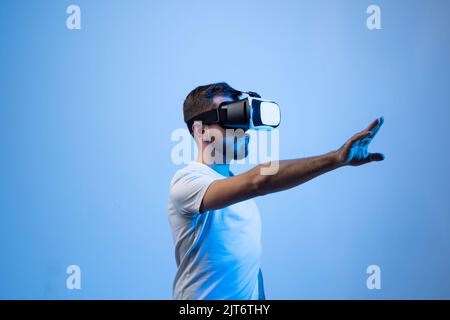 Young bearded man wearing VR headset to watch 3d virtual video with AR experience. Future of online streaming in metaverse. Stock Photo