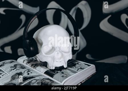 a white plaster skull wearing headphones on a comic book black and white background. halloween theme. Stock Photo