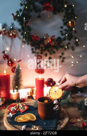mulled red wine gluhwine in cup with orange, christmas decor table with candles Stock Photo