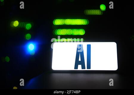 AI logo on the phone screen on the background of the server room. Smartphone with artificial intelligence neural network logo Stock Photo