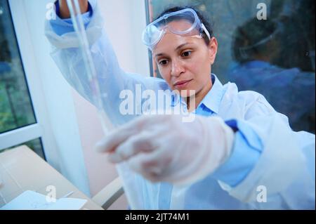 Close-up. Female scientist pharmacologist using glass graduated laboratory pipette, titling a chemical into a test tube Stock Photo