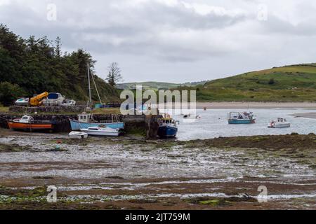 Clonakilty, Ireland, July 2, 2022. An jetty and several moored fishing boats in Clonakilty Bay. Fishing boats anchored at low tide. Shallow sea, lands Stock Photo