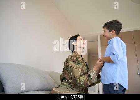 Mom soldier and son communicate cutely in a bright room Stock Photo