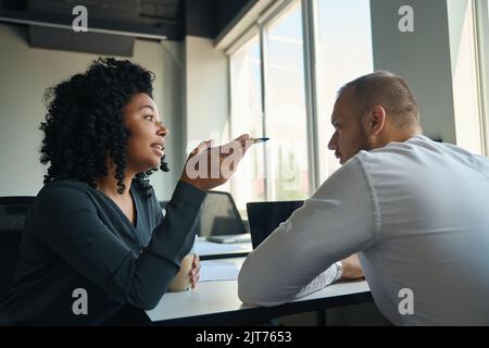 Employees chatting at a desk in a simple bright office Stock Photo