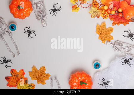 Halloween frame. Skeletons pumpkin spiders autumn leaves on a white gray background. Stock Photo