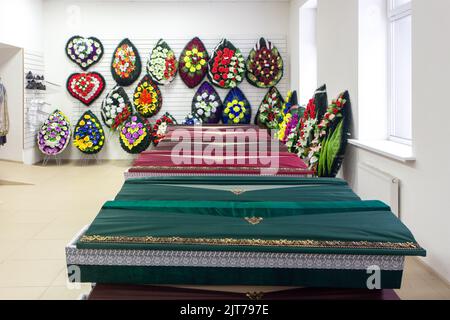 Interior of room with funeral accessories. Shop selling coffins, funeral wreaths and flowers. Stock Photo