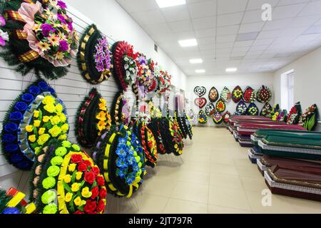 Interior of room with funeral accessories. Shop selling coffins, funeral wreaths and flowers. Stock Photo