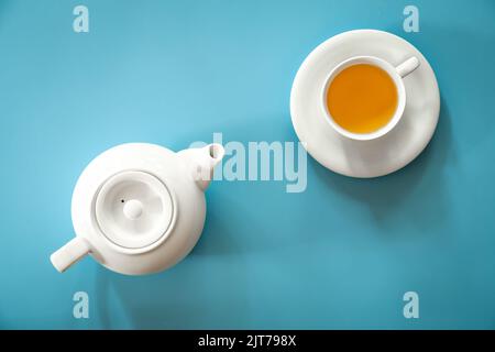 Cup of tea and teapot on a blue background, flat lay. Stock Photo