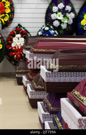 Interior of room with funeral accessories. Shop selling coffins, funeral wreaths and flowers. Stock Photo