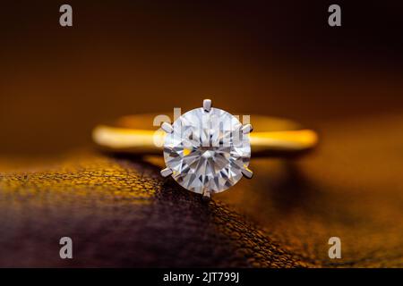 Classic solitaire gold ring with round cut diamond with soft yellow light Stock Photo