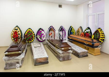 Interior of room with funeral accessories. Shop selling coffins, funeral wreaths and flowers. Stock Photo