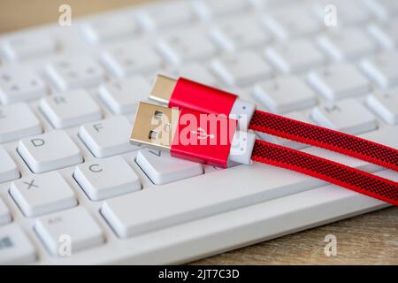 Close-up on an USB Type C cable with a white keyboard in the background Stock Photo