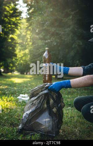 Close-up, a plastic bottle in a male hand, cleaning up nature. Stock Photo