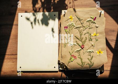 Dry pressed plants and flowers on a wooden table. DIY, hobby Stock Photo