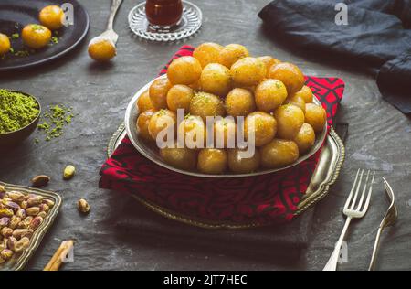 Arabic Cuisine; Middle Eastern traditional dessert/Ramadan dessert 'Zalabya', or Luqmat Al-Kadi served with honey and pistachio. Stock Photo