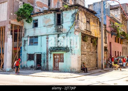Cuban people are by a run-down building in a city corner. The image shows the poverty and economic failure of the communist system Stock Photo