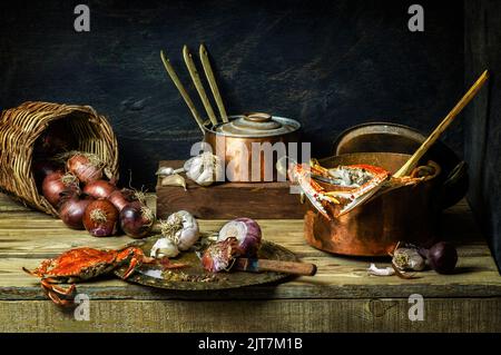 Still life food with fresh crabs placed in old copper pot with basket of onions, and garlic on rustic wooden background. Stock Photo