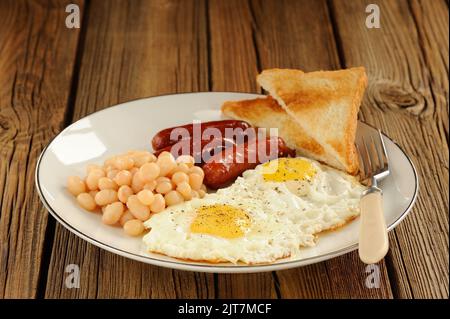 Full english breakfast with eggs, sausages, beans, toasts  on wooden background Stock Photo