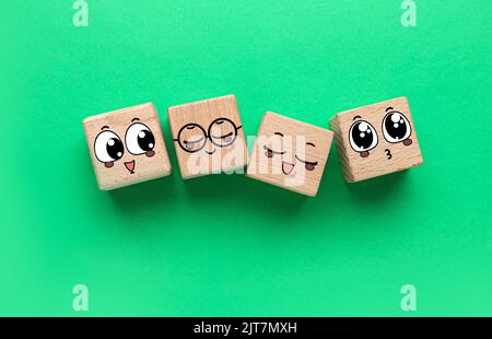 Wooden cubes with different drawn emoticons on green background Stock Photo