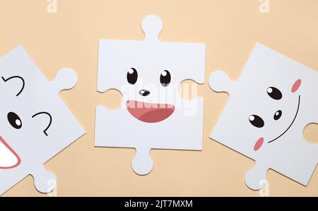 White puzzle pieces with different drawn emoticons on beige background Stock Photo
