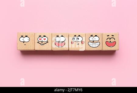Wooden cubes with different drawn emoticons on pink background Stock Photo