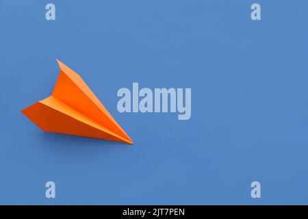 Orange paper plane on blue background Stock Photo
