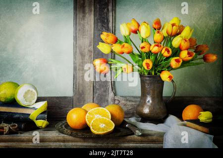 Classic still life with bouquet of tulips flowers placed with fresh oranges, scarf and vintage books on rustic wooden table. Stock Photo