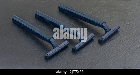 three disposable razors on dark stone background Stock Photo