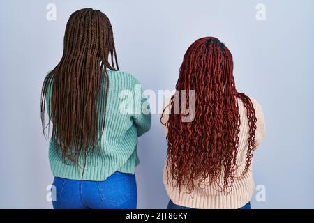 Two african woman standing over blue background standing backwards looking away with crossed arms Stock Photo