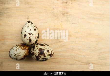 three quail eggs on a cutting board Stock Photo