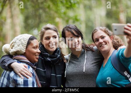 Making memories in the great outdoors. a group of friends taking a selfie while out on a hike. Stock Photo