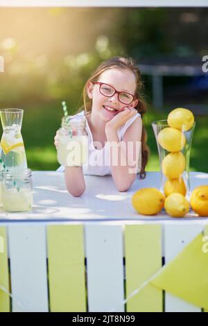 Its freshly squeezed. Portrait of a little girl selling lemonade from her stand outside. Stock Photo