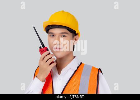 Portrait young asian man is engineer wearing helmet standing and using radio for speak with confident isolated on white background, handsome male is a Stock Photo