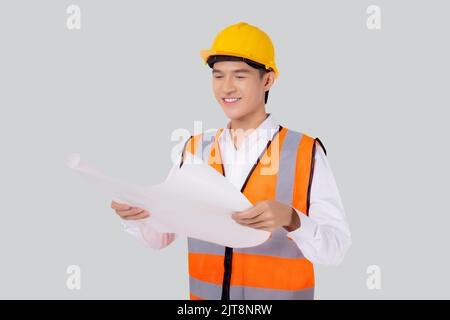 Portrait young asian man is engineer wearing helmet holding and looking blueprint with confident isolated on white background, handsome male is archit Stock Photo