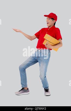 Young asian man in uniform red and cap standing carrying box stack isolated white background, employee holding cargo or package, courier and delivery, Stock Photo