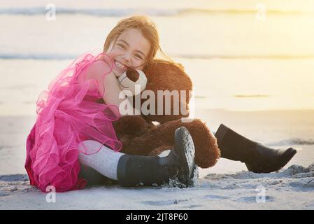 I love my bear. Portrait of a cute little girl playing with her teddy bear on the beach.