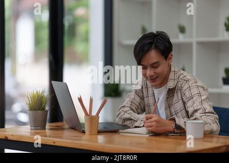 Graphic designer drawing in notebook and using laptop at home. Creative concept Stock Photo