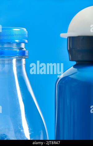 Pair of bottles, a plastic transparent disposable one and a blue metal reusable one. Concepts: sustainability, recycling, reusing, pollution, zero was Stock Photo