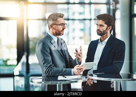 Consolidating their ideas with smart apps. two colleagues using a digital tablet together in a modern office. Stock Photo
