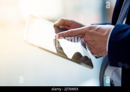 Modern tools for the modern man. Cloesup shot of a businessman using a digital tablet while standing in an office. Stock Photo