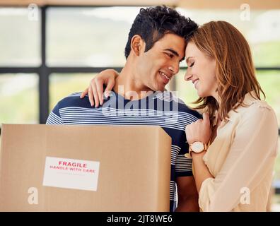 Together they make a house a home. a affectionate young couple carrying boxes on moving day. Stock Photo