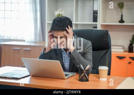 Tired depressed bored and Panicked businessman Stressed working in contemporary office looking at laptop feel problem at work casual attire workplace Stock Photo