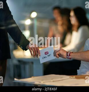 Sealed with a big kiss. Closeup shot of a love note being passed from one colleague to another. Stock Photo