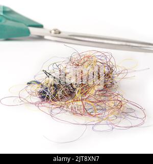 tangled colorful sewing threads with a pair of scissors, isolated on white background, soft-focus Stock Photo