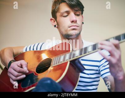 Hes got the music in him. a handsome young man playing guitar at home. Stock Photo