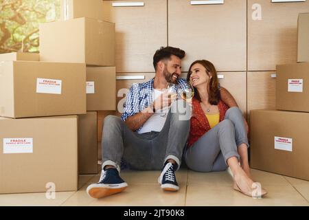Heres to achieving this milestone together. a young couple celebrating their move into a new home. Stock Photo