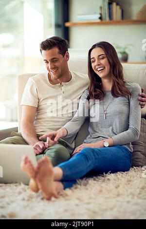 Couple goals Sharing the same taste in movies. a relaxed young couple using a laptop together at home. Stock Photo